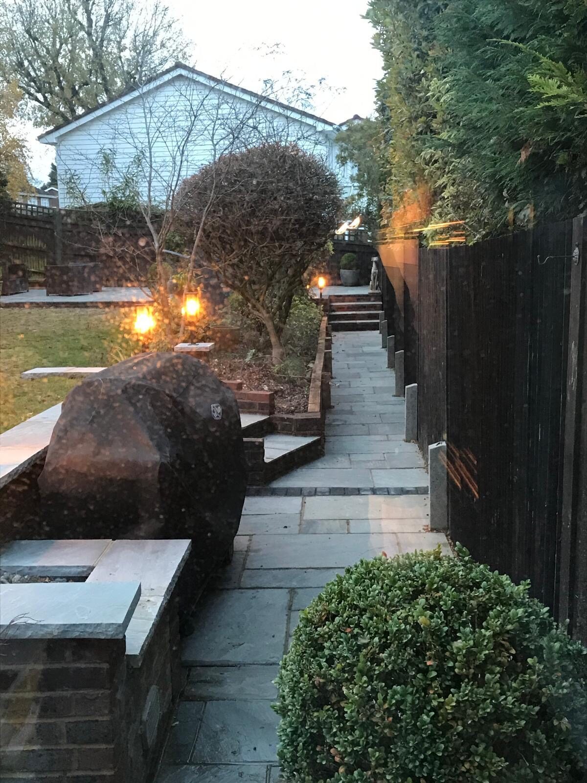 Landscaped garden with lighting and water feature at dusk in Surrey