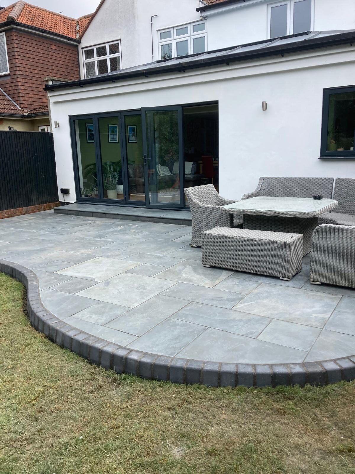 Grey porcelain patio with seating area and lawn in Surrey