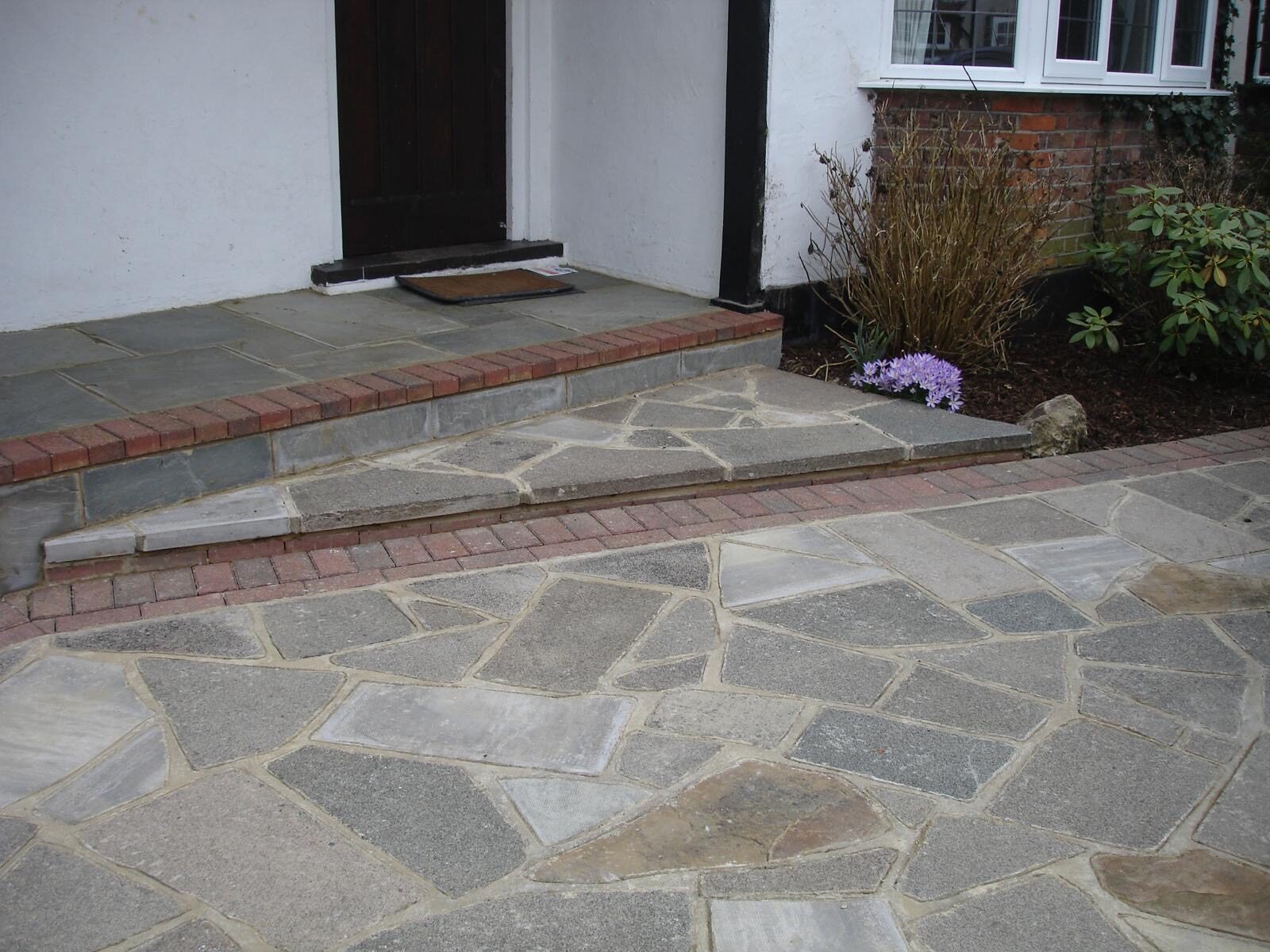 Natural stone driveway to a white rendered home in Surrey